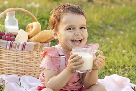 快乐的孩子喝牛奶在盛开的花朵中野餐生日快乐图片