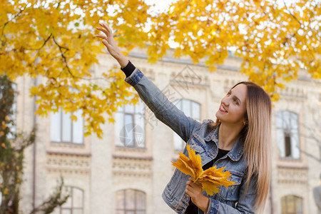 女士手握着黄色叶子阳光秋天的概念是图片