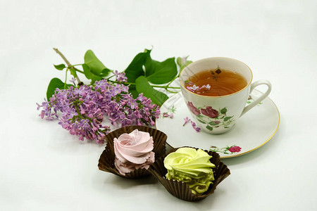 茶在瓷杯中粉色和黄色棉花糖白面上紫色图片