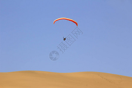 在降落伞降落前的自由坠落期间从沙丘跳跃和在空气中进行杂技操图片