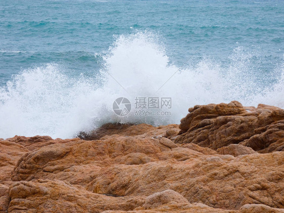 大浪拍打着海岸的沙子和岩石图片