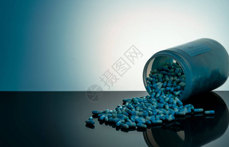 地瓜丸蓝色和白色胶囊丸从白色塑料瓶容器中溢出全球医疗保健概念抗生素耐药抗菌胶囊丸医背景