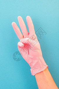 指向三号用粉红色手套在蓝背景图片