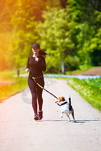 运动女孩在春天带着一条狗Beagle跑来去图片