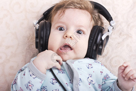 戴着大耳机的婴儿听音乐的孩子很惊讶背景图片
