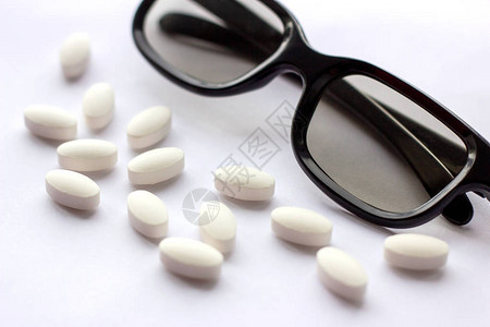 浅色背景上带眼镜的白色药丸和平板电脑药学和医学概念专注于眼科疾病的制药行业选背景图片