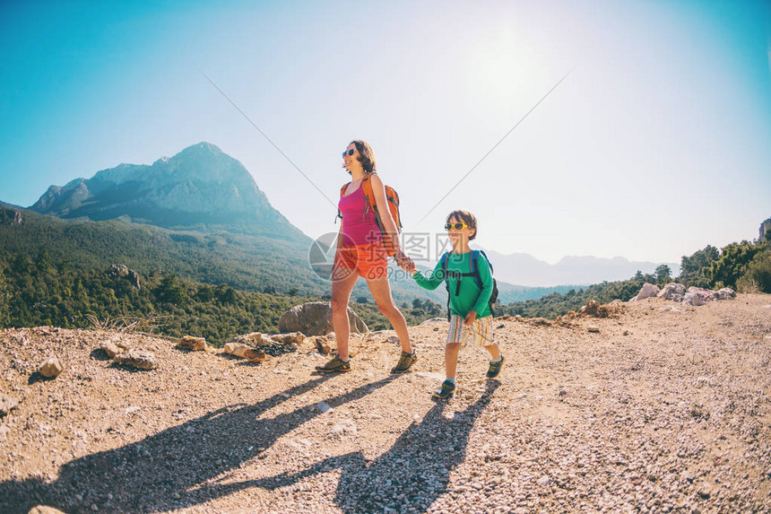 男孩和他的母亲站在山顶上一个女人带着孩子旅行男孩和他的母亲一起看山背着包旅行和孩子一图片