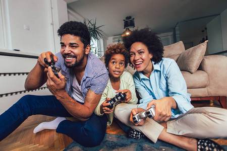 微笑的家庭坐在沙发上一起玩电子游戏图片