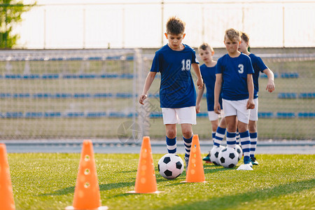 孩子们的足球训练营男孩们在操场上练习足球运员发展足球运技巧孩子们用球和锥体训练足球激流回旋训练以提高图片