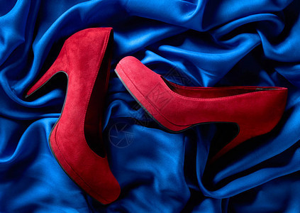 红色女人的骨髓鞋在蓝色丝绸背图片