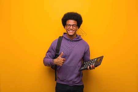 年轻非洲美国学生男子拿着计算器笑着抬起图片