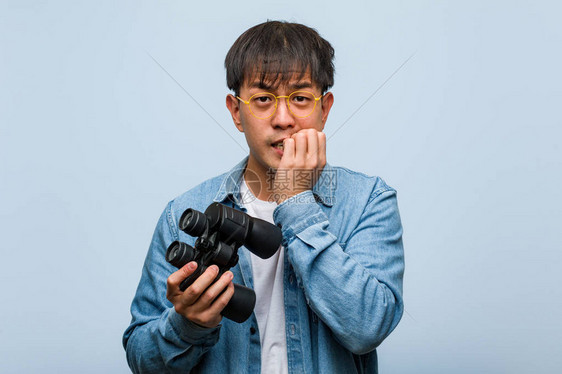 年轻人拿着双筒望远镜咬指甲紧图片
