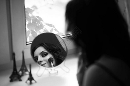 美丽的女孩在镜子前化妆图片