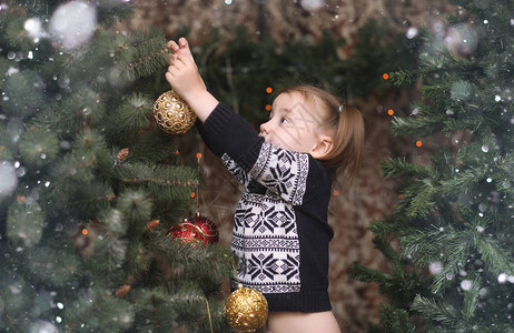 树旁的小孩圣诞树上装饰图片