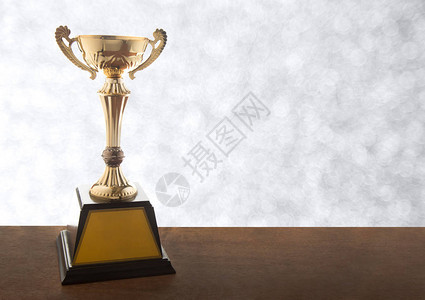 金奖杯在布基背景的木桌上以复制图片