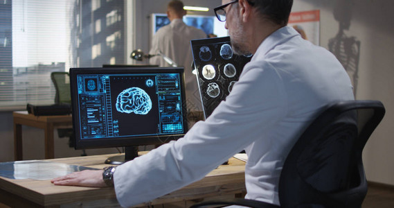在监测和分析X射线和脑扫描时坐在监控台的图片