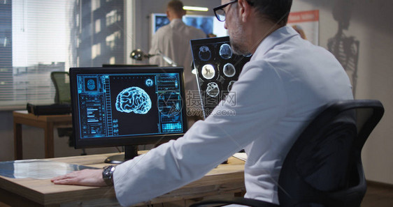 在监测和分析X射线和脑扫描时坐在监控台的图片