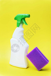 喷雾中的化学品清洁剂和黄色背景的紫海绵图片