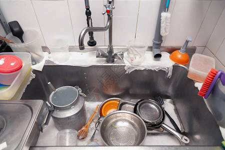 专业餐厅厨房的金属平方水槽中紧贴的脏器械堆图片