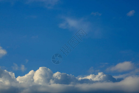 阳光透过蓬松的白云在湛蓝的天空背景下图片