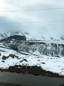 美丽的山区寒冷冬季度假胜地景观与高山峰雾和白雪覆盖的岩石滑雪板和图片