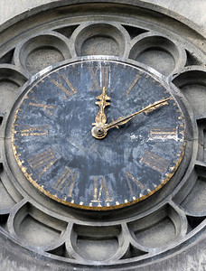 古老的有风气的教堂塔钟在雕刻的石头上被罗曼数字和金手背景图片