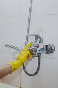 家庭主妇清洁浴室水龙头和淋浴水龙头戴着黄色防护手套的女仆洗脏浴缸水龙头妇女洗手或图片