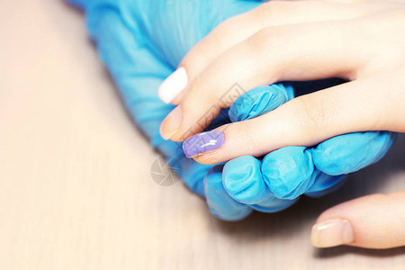 在美容院缝合健康的自然女人的指甲修造手绘画客户的指甲图片