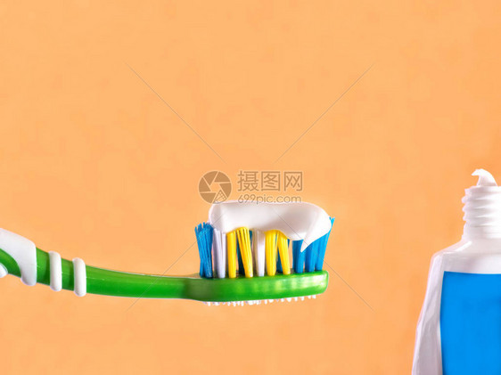 牙刷挤在牙刷膏橙色背景上图片