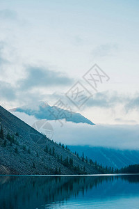 山和低云的惊人剪影反映在高山湖泊上水镜上的美丽涟漪高地多云的天空大气的幽灵景观美背景图片