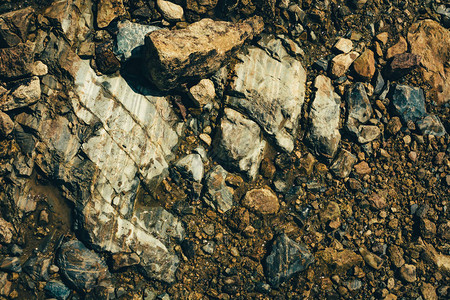 在水特写镜头上的原矿阳光下的多色湿原石纹理生动的地质背景与一堆粗鲁的石头自然纹理与复制空间惊人的矿图片