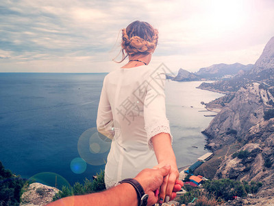 女孩在暑假旅行度假的夏日用她男朋友的手对着悬崖的图片
