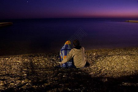 两对情侣在夜晚坐在海边在月亮和星的光照下在一个图片