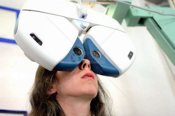 女年轻少女通过自动眼科设备低深度田野的透镜安装程序图片
