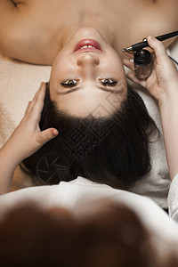 一个可爱的年轻女人看镜头时由美容师在温泉沙龙做氧气处图片