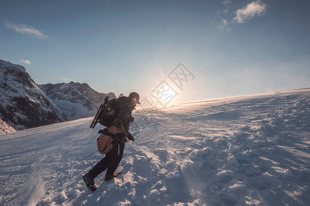 人类摄影师在雪山上攀爬在落日的蓝图片