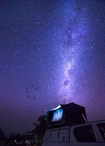 银河系在位于纳米比亚纳米布沙漠中一辆皮卡车顶上的帐篷上与许多星图片