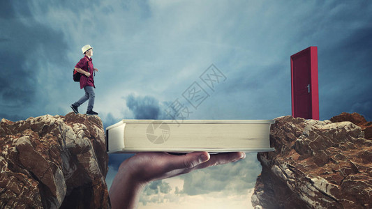 年轻人在一本书上从山顶传到另一本书图片