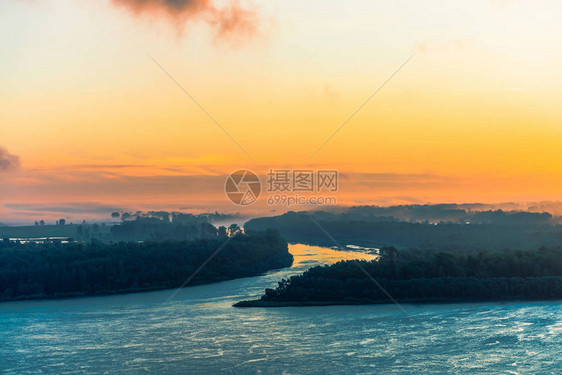 蔚蓝的河流沿着岸边流淌着雾下的森林河道环绕岛屿流动黎明天空中的橙色光芒五颜六色的早晨神秘大气图片