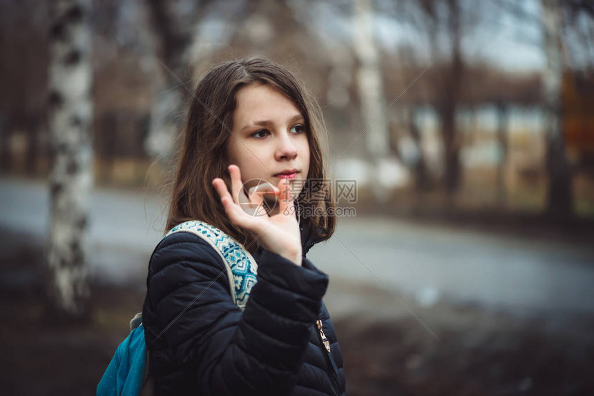 背着包的女学生在阴雨中沿着城市街道走在沮丧的状态头发湿漉的年轻女孩在户外有复制空间忧郁的图片