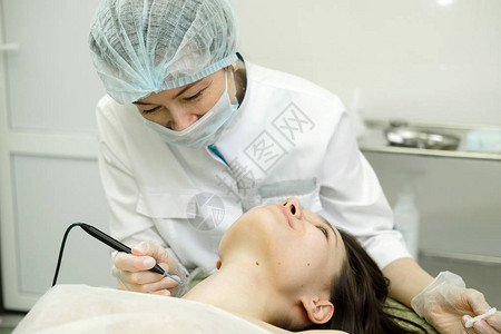 从女患者的脖子上去除胎记的医学治疗使用电烙器去除痣的女皮肤科医生无线电波凝图片