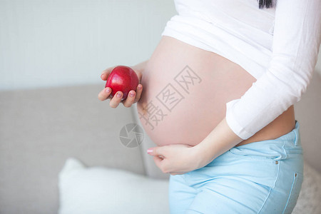有苹果的可爱的孕妇期待女人拿着健康的食物夫人吃一个红苹果为怀孕提图片