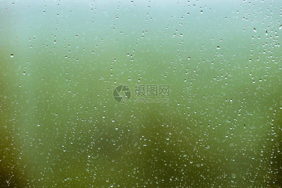 有雨滴的脏玻璃绿色清晰散景背上的雨滴窗外绿意盎然水滴和污渍关闭宏中详图片