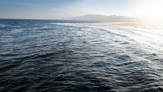 海岸上平静的海洋和山脉的美丽景观海浪在日落光下在死珊瑚礁和岩石图片