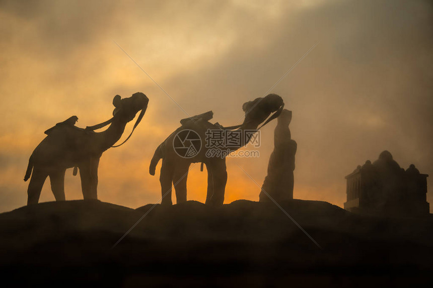 日落时穿过沙漠丘的骆驼大篷车东部旅行概图片
