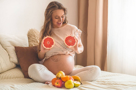 怀孕和健康的有机营养怀孕和葡萄柚孕妇在床上享受新鲜水果图片