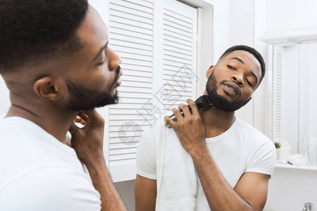 非洲男子在浴室照镜子刮胡须的非洲男图片