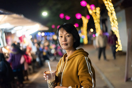 亚裔女在夜市上喝着著名的图片