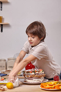 鼻子和手上涂着糖粉的帅小男孩正在厨房做一个自制蛋糕图片