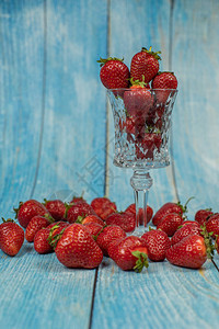 蓝色木制背景上的玻璃杯中的草莓特写新鲜成熟的红色有机浆果放置您图片
